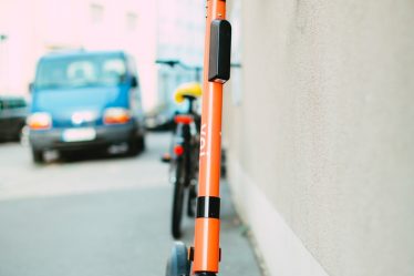 black and orange scooter parked on sidewalk
