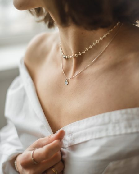 woman in white off shoulder shirt wearing silver necklace