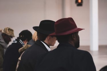 man in black suit wearing brown fedora hat