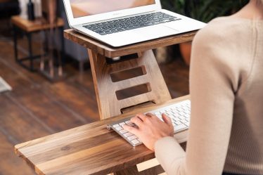 woman in white long sleeve shirt sitting on brown wooden chair using macbook air