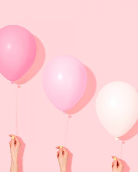 person holding pink and white balloon
