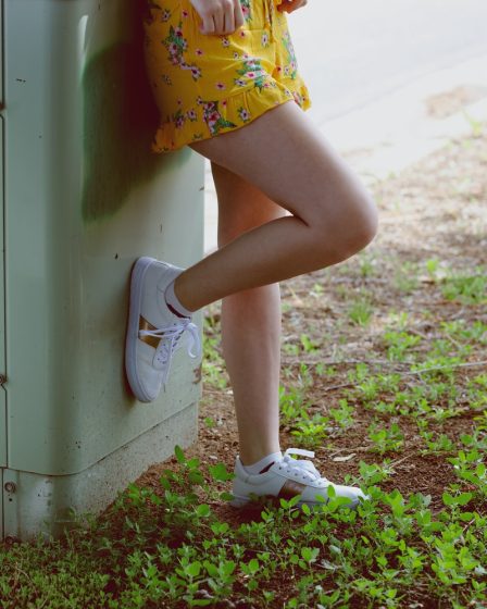woman in yellow miniskirt leaning on gray panel