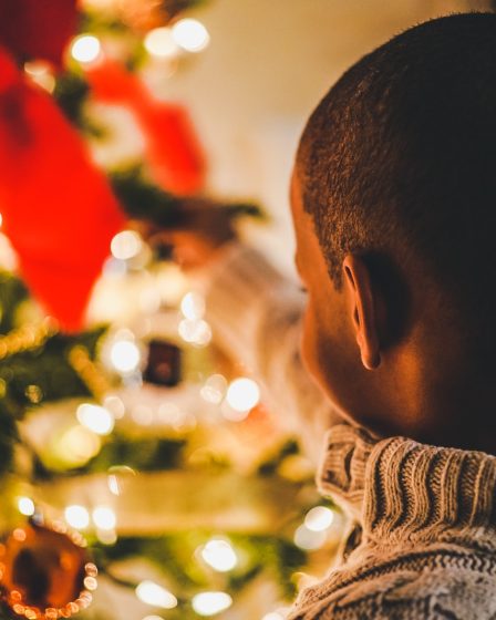 selective focus photography of boy near lit Christmas tree