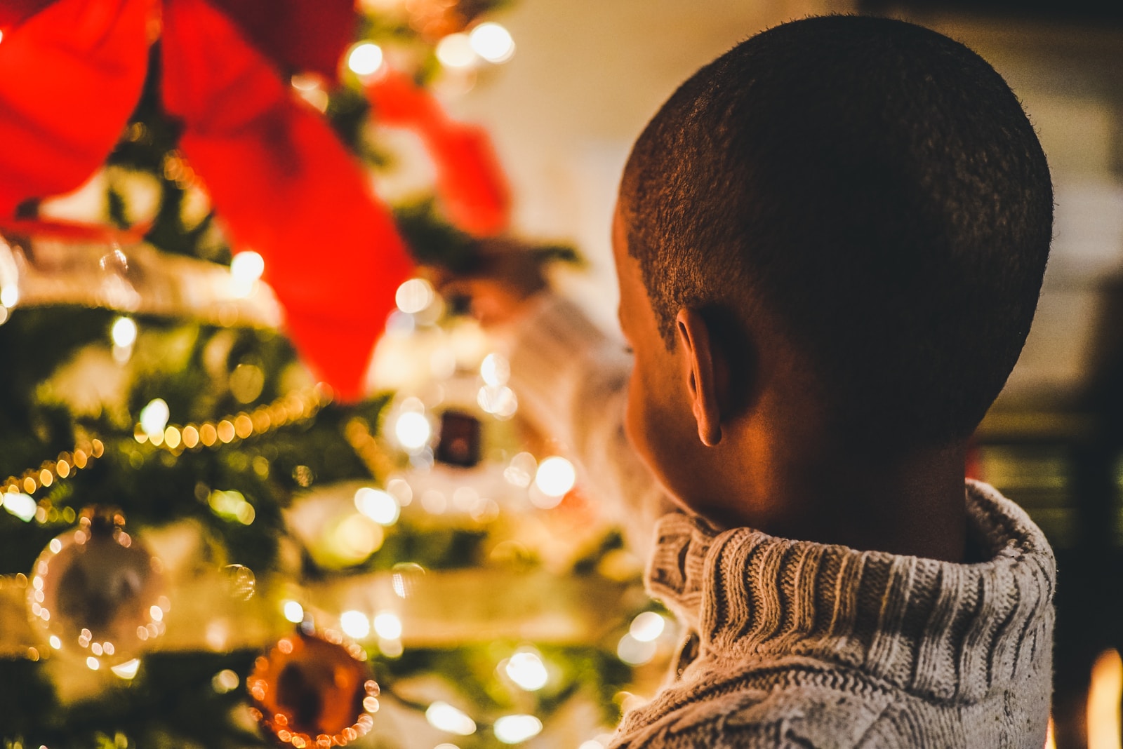 selective focus photography of boy near lit Christmas tree