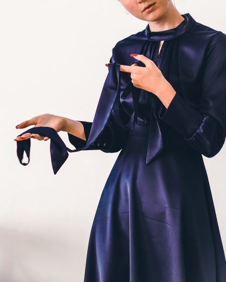 woman in black long sleeve dress holding black leather handbag