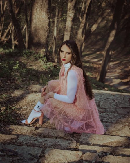 girl in pink dress sitting on brown rock