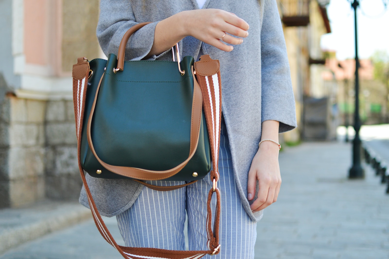 women standing while carrying green and brown leather 2-way shoulder bag