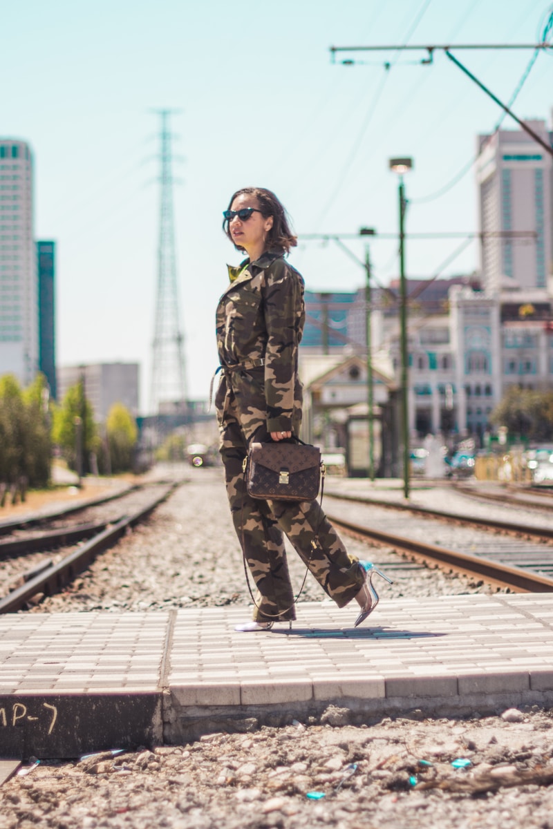 woman wearing camouflage soldier uniform carrying brown 2-way leather bag