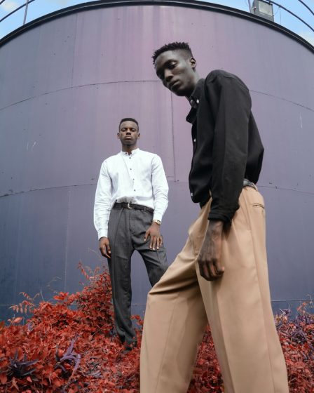 two men standing on red flower in front of gray metal wall