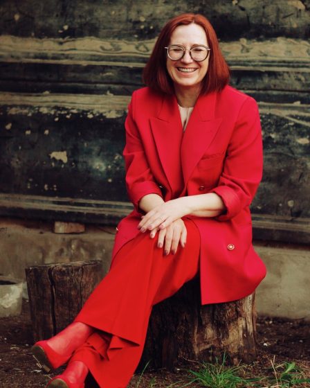 woman in red blazer and black skirt sitting on brown concrete stairs